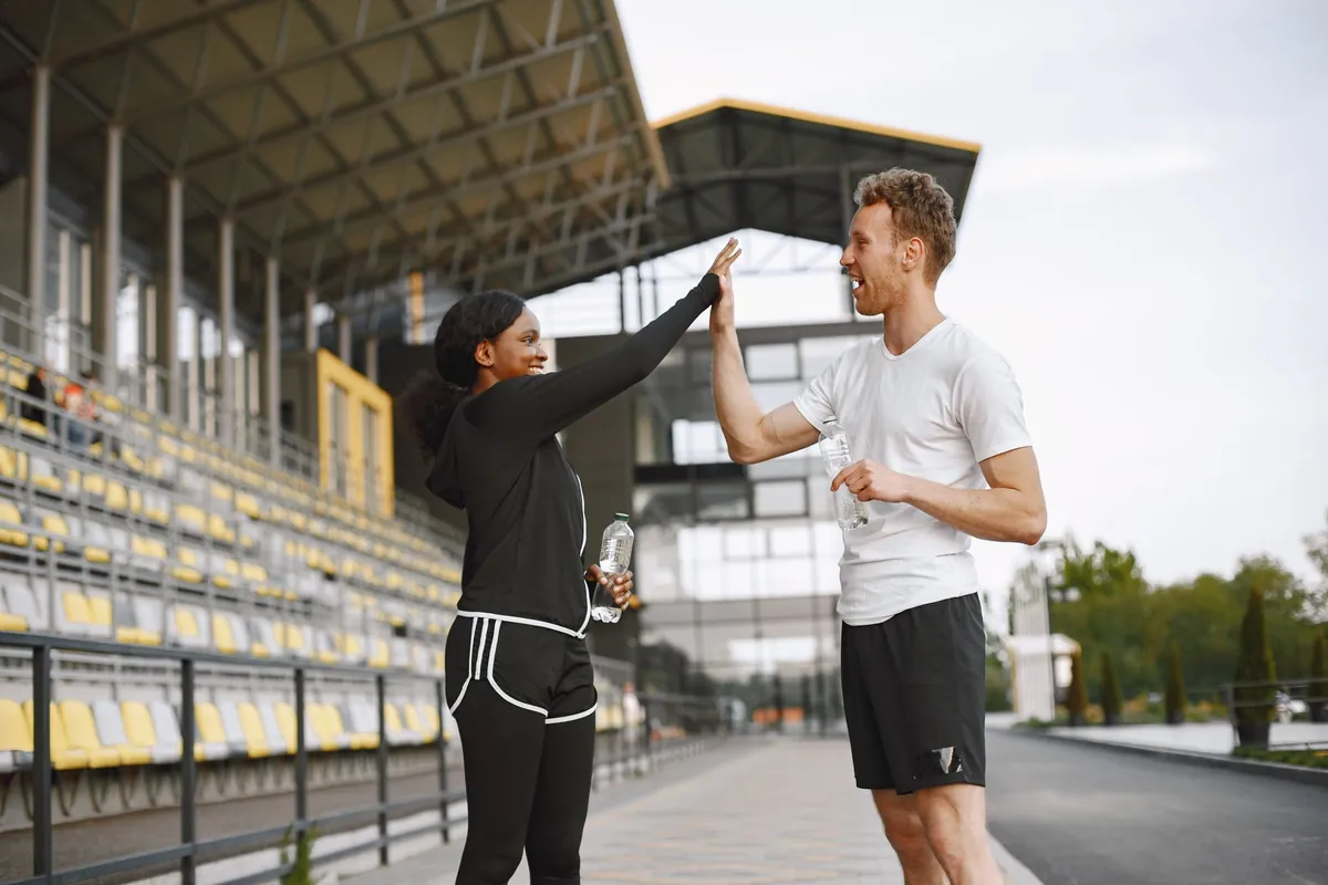 Twee sporters geven elkaar een high five op een sportpark na een gezamenlijke training