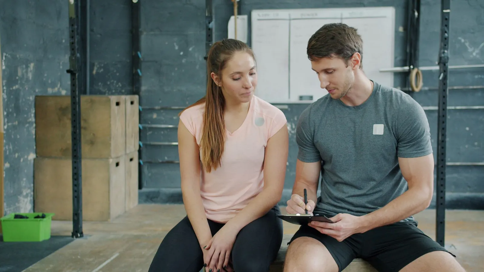 Personal trainer en sporter bespreken samen een trainingsschema op een tablet in de sportschool
