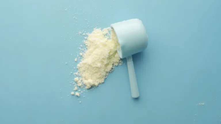 Maatschepje met wit poeder op een lichtblauwe ondergrond, zoals een dagelijkse portie creatine